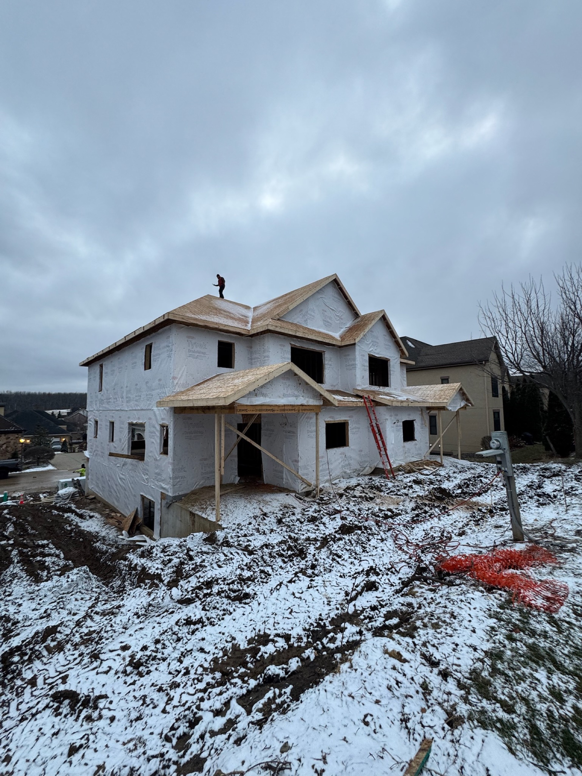 Framer on rooftop of two-story home in winter build