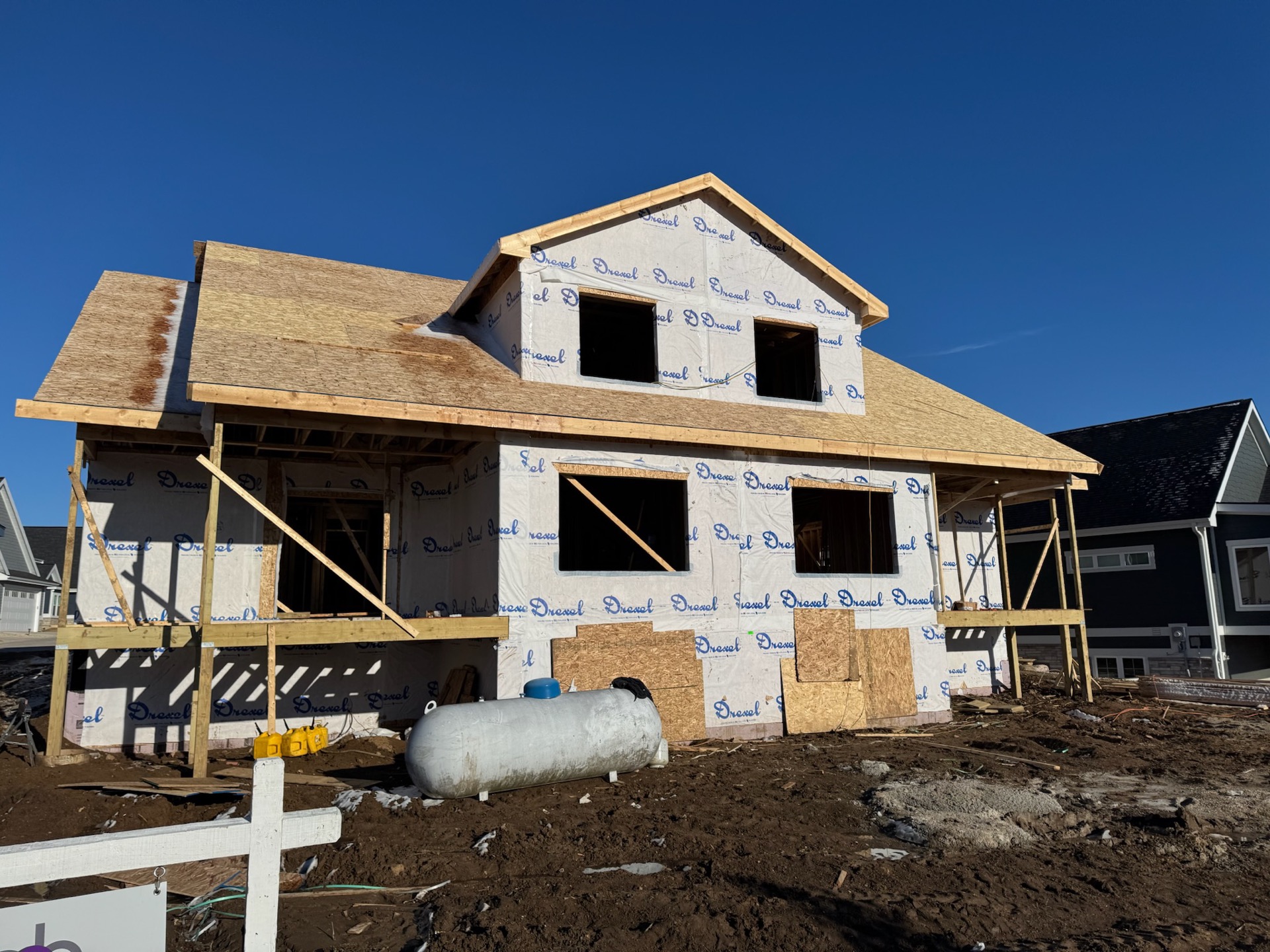 Two-story luxury custom home framing under blue sky